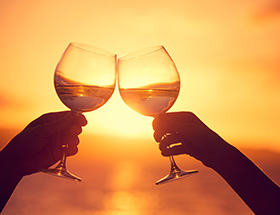 Couple clinking wineglasses at sunset